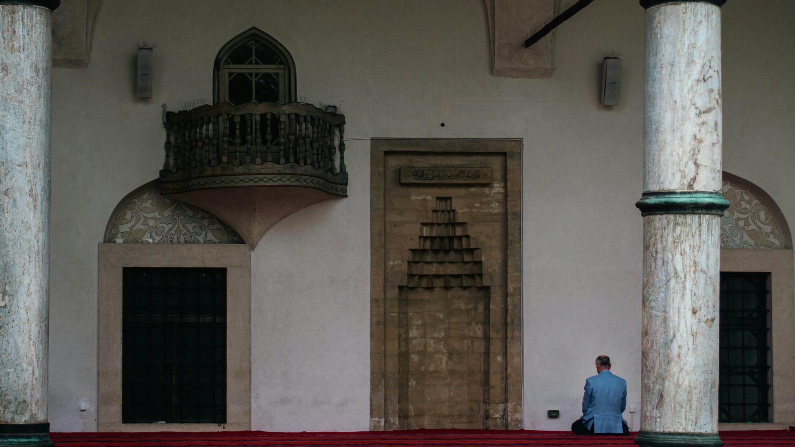 pexels-photo-12898111-12898111 Man in prayer at historic mosque in Sarajevo, showcasing intricate architectural details.