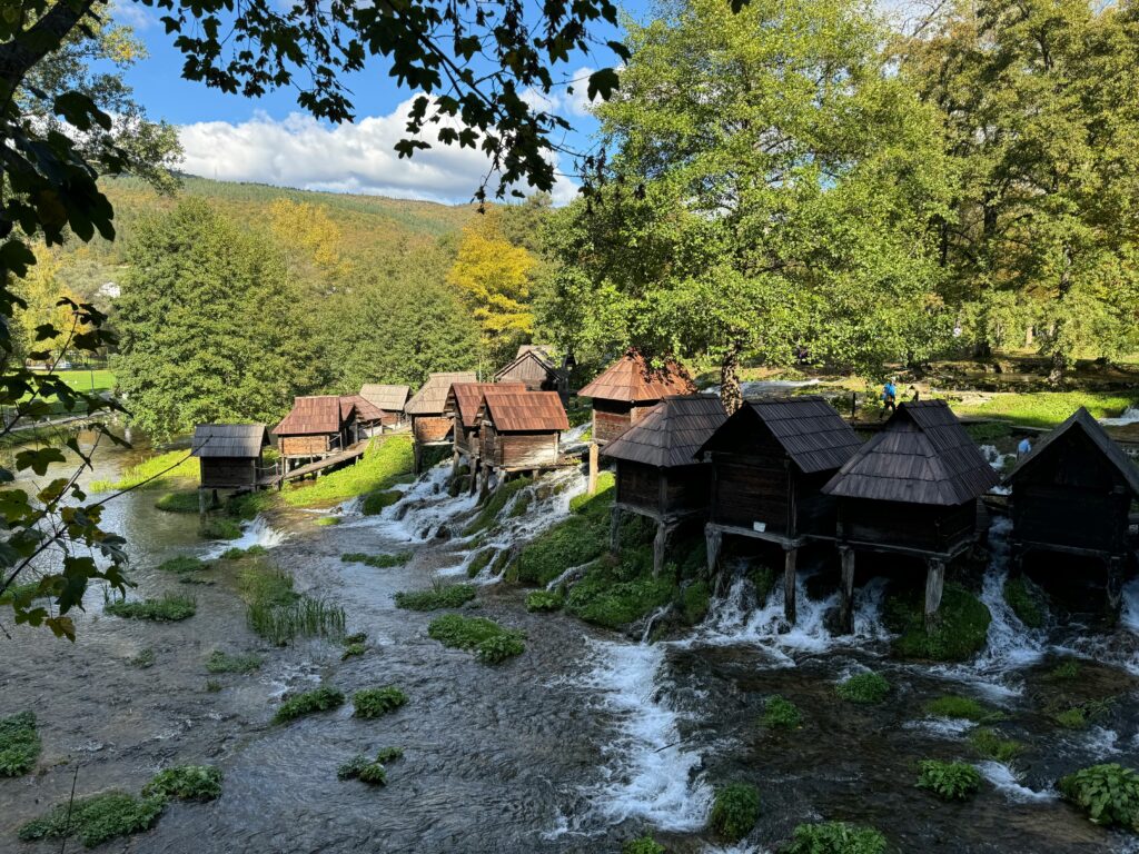Rustic watermills along the Pliva River amidst vibrant autumn foliage in Bosnia.