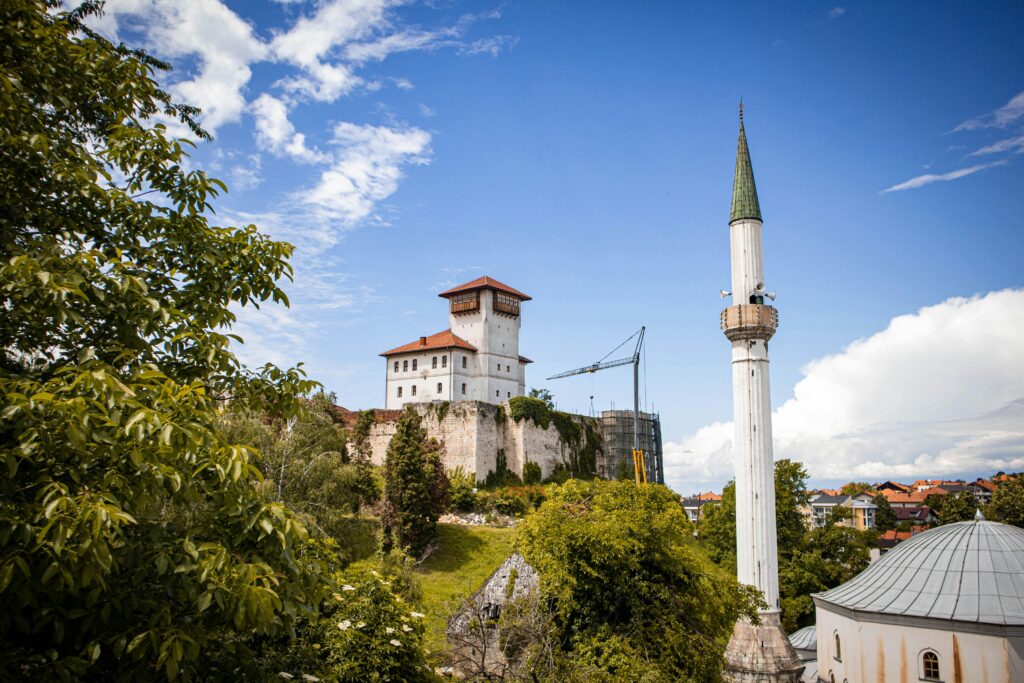 pexels-photo-32247015-32247015 A stunning view of Gradačac Castle and minaret surrounded by lush greenery under a bright blue sky.