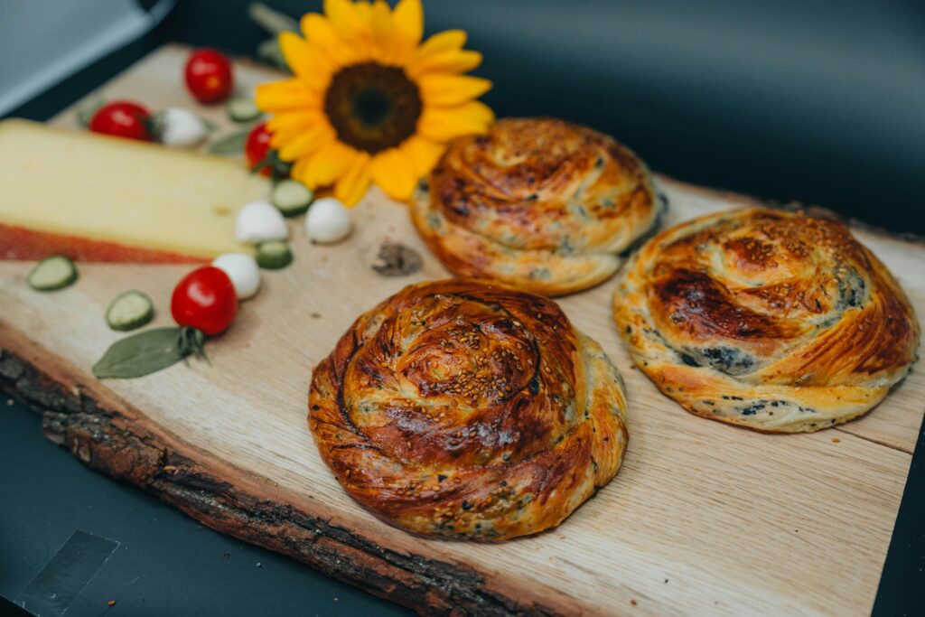 pexels-photo-28219386-28219386 Artistic food photo featuring brea bosnian pastries d rolls with cheese and sunflower on wooden platter.