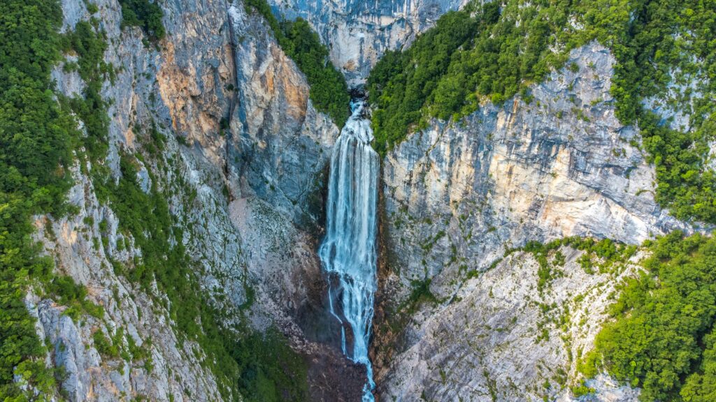 pexels-photo-8737699-8737699 A breathtaking view of a waterfall cascading down a rocky mountain surrounded by lush greenery.